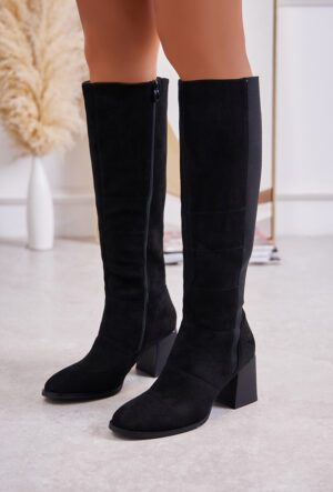 Ces bottes cavalières en noir présentent une silhouette élancée avec une tige haute. Le design est minimaliste, avec un zip latéral pour un enfilage facile. Elles sont dotées d'un talon bas et d'une semelle plate pour un confort optimal. La matière est lisse et légèrement brillante, créant un aspect élégant et intemporel.